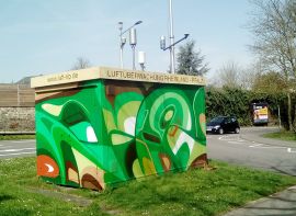 Ein mit grünen Graffitis bemaltes Gehäuse an einer Straße