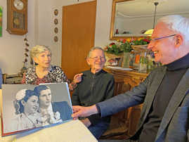 OB Wolfram Leibe zu Besuch beim Gnadenhochzeitspaar Schmitt, wobei er ein Album mit dem hochzeitsbild des Paares aufgeschlagen hat.