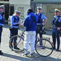 Vier Mitarbeiter des Ordnungsamts umringen eine Person mit einem Fahrrad in der Fußgängerzone