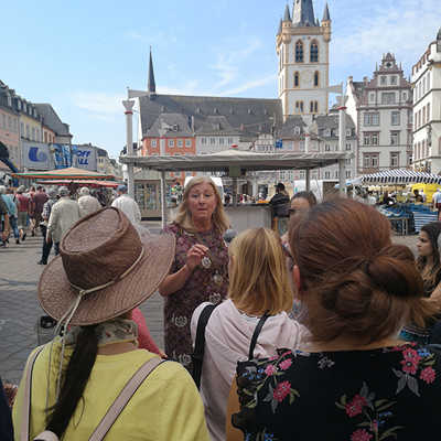 Stadtführerin Christiane Salm-Schenten macht beim neuen Weinrundgang „Moselwein trifft Geschichte“ Station auf dem Hauptmarkt. Foto: TTM 