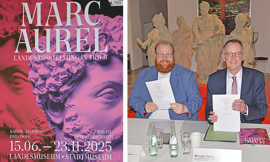 Das zweigeteilte Bild zeigt links ein Plakatmotiv mit der Aufschrift "Marc Aurel" über einem roten und einem pinken Kopf, die in entgegengesetzte Richtungen blicken. In der rechten Bildhälfte präsentieren Markus Nöhl und Michael Ebling jeweils ihr Exemplar der unterzeichneten Vereinbarung.