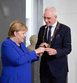 OB Wolfram Leibe überreicht Bundeskanzlerin Angela Merkel eine römische Münze als Gastgeschenk.